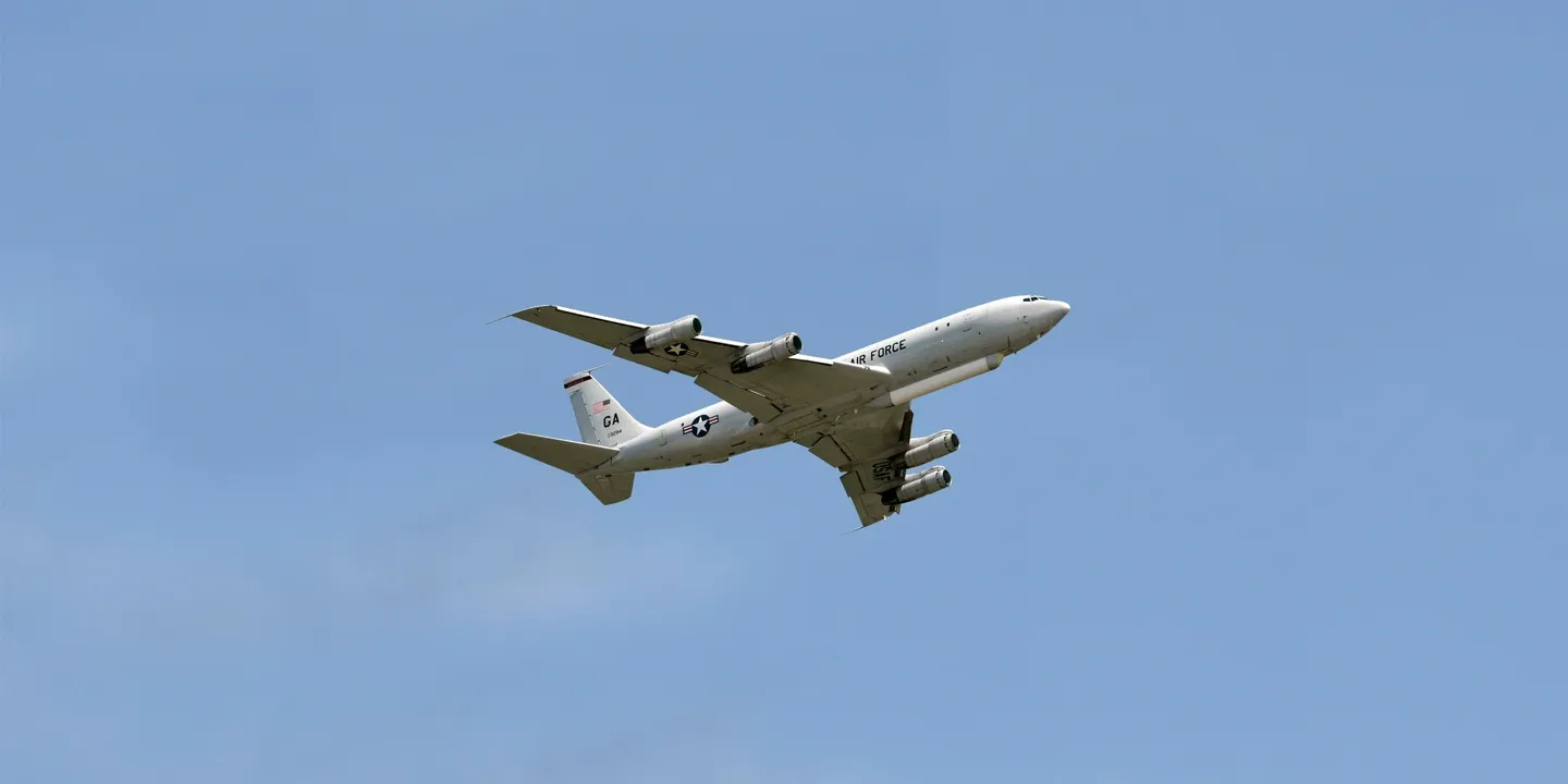 A large airplane flying in the sky with its landing gear down.