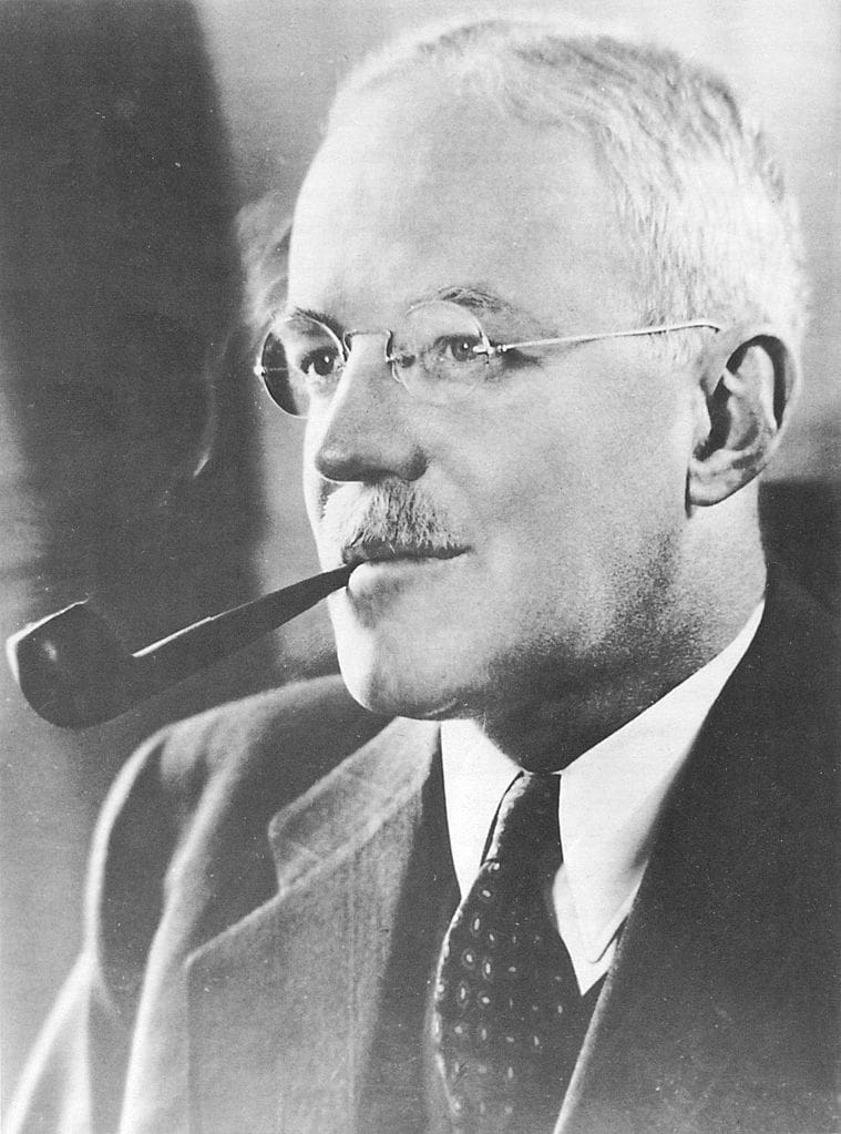 A man with glasses and a pipe in his mouth.