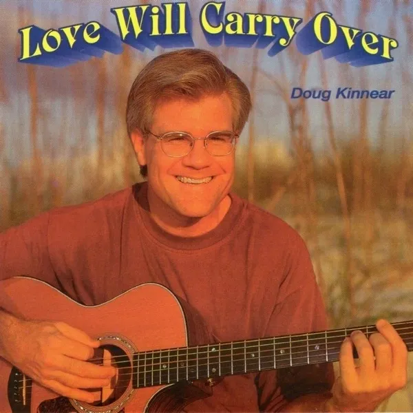 A man holding a guitar in front of trees.