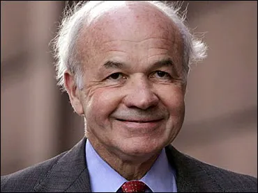 A man with white hair and wearing a suit.