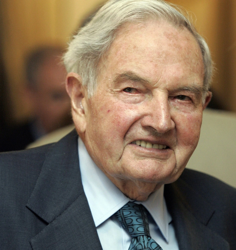 A man in suit and tie with white hair.