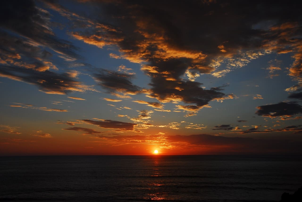 A sunset with clouds in the sky over the ocean.